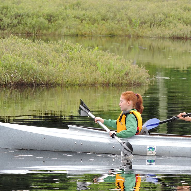 Girl paddling in a kayak on Muddy Pond