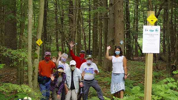 A group of people waving near the entrance of the new Sunset View Farm hiking trail.
